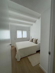 a white bedroom with a bed and a window at Habitatges Turístics Riba Pitxot - S'Arenella in Cadaqués