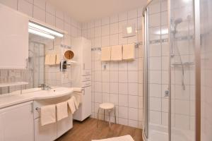 baño blanco con ducha y lavamanos en Landhotel Gressenbauer en Hinterstoder