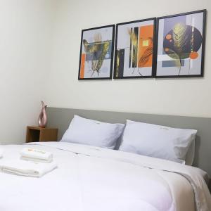 a bedroom with a white bed with four pictures on the wall at VR2 Hotel in Lençóis Paulista