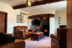 a living room with leather furniture and a fireplace at Cynynion Uchaf - Countryside Farmhouse with Views in Oswestry