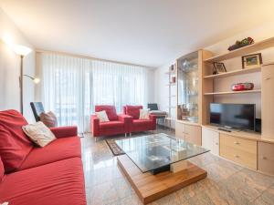 a living room with a red couch and a tv at Haus Tarbey in Leukerbad