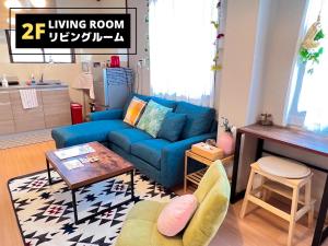 a living room with a blue couch and a table at Jen's House Osaka in Osaka