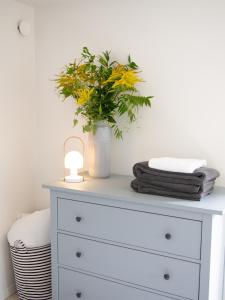 a white dresser with a vase of flowers on it at Kamilla's cottage, 1 km. from the beach in Stege