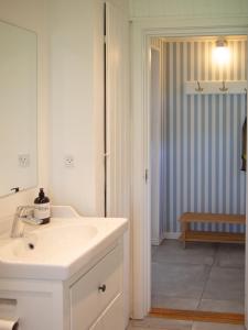 a white bathroom with a sink and a mirror at Kamilla's cottage, 1 km. from the beach in Stege