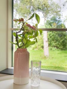a vase with a plant in it next to a window at Kamilla's cottage, 1 km. from the beach in Stege