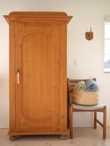 um armário de madeira ao lado de uma cadeira e uma cesta em Kamilla's cottage, 1 km. from the beach em Stege
