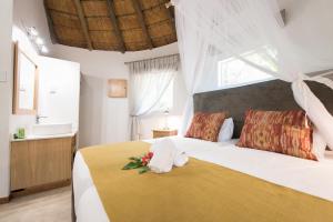 Un dormitorio con una gran cama blanca con flores. en Sefapane Lodge and Safaris en Phalaborwa