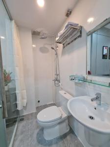 a white bathroom with a toilet and a sink at SUN HOTEL in Hue