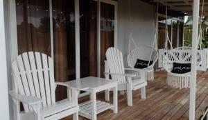 een groep witte stoelen en een tafel op een veranda bij Angels Bed and Breakfast Sipalay City by RedDoorz in Sipalay