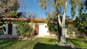 a house with a white garage and a tree at Danaides Bungalows in Tolo