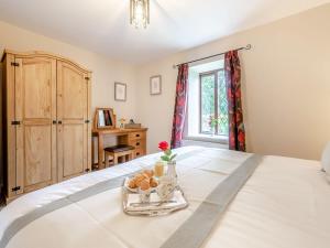 a bedroom with a bed with a tray of food on it at Llanfair Hill Cottage in Cwrt-newydd