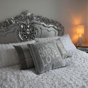 Una cama con una cabecera de plata con una almohada con las palabras que los asesinos necesitan amor en Ugthorpe Lodge Hotel en Whitby