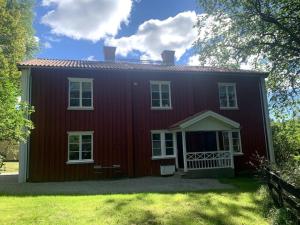 uma casa vermelha com janelas brancas e um quintal em Brunsbergs Herrgård appartement em Brunskog