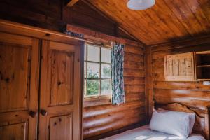 um quarto de um chalé de madeira com uma cama e uma janela em The Jonas Centre em Leyburn