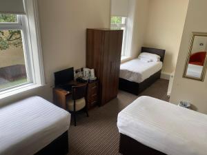 a hotel room with two beds and a desk with a computer at The New Brighton Hotel in New Brighton