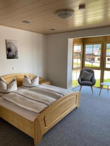 1 dormitorio con 1 cama grande y 1 silla en Landgasthof Brandtner Wirt, en Langdorf
