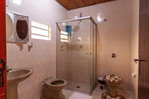 ein Bad mit einer Dusche, einem WC und einem Waschbecken in der Unterkunft Chalés Dona Zenta in Monte Verde