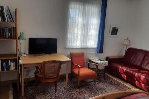 a living room with a desk with a television and a couch at Paulus Gästehaus Top 2 in Salzburg