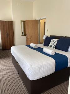 a large bed with blue and white sheets in a room at The New Brighton Hotel in New Brighton