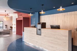 an office lobby with a reception counter and blue walls at B&B HOTEL Porto Expo Aeroporto in Matosinhos