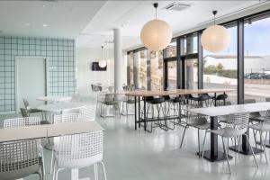 un restaurant avec des tables blanches, des chaises et des fenêtres dans l'établissement B&B HOTEL Porto Expo Aeroporto, à Matosinhos