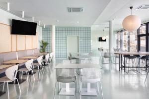 a restaurant with tables and chairs and a flat screen tv at B&B HOTEL Porto Expo Aeroporto in Matosinhos