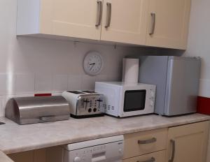 encimera de cocina con microondas y electrodomésticos en Garden Cottage, Five Pines en Acton Turville