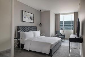 a hotel room with a white bed and a chair at Steigenberger Residence Doha in Doha