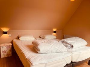una camera con 2 letti con lenzuola e cuscini bianchi di Casa Monica a Malmedy