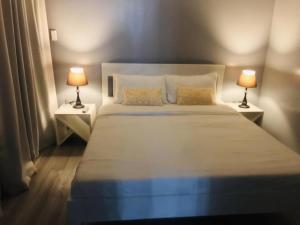 een slaapkamer met een groot wit bed met 2 lampen bij Angels Bed and Breakfast Sipalay City by RedDoorz in Sipalay