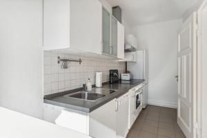 een keuken met een wastafel en witte kasten bij Bright 3-room apartment near Prenzlauer Berg in Berlijn
