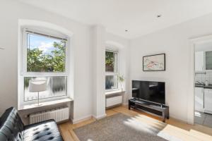 a living room with a couch and a tv and two windows at Bright 3-room apartment near Prenzlauer Berg in Berlin
