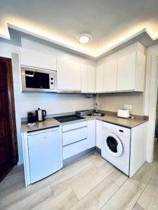 a kitchen with white cabinets and a washing machine at Apartament Bonaire in L'Escala