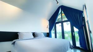 a bedroom with a bed with blue curtains and a window at Kampot Riverfront Boutique in Kampot