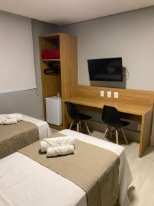 Habitación con 2 camas y escritorio con TV. en HOTEL CORTESE en Teresina