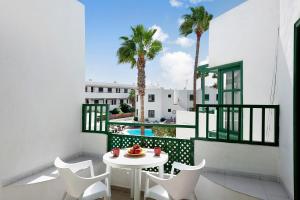 einen Balkon mit einem Tisch, Stühlen und einem Pool in der Unterkunft Spacious Sunny Relaxing Lanzarote in Puerto del Carmen