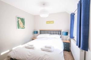 a bedroom with a large white bed with blue curtains at Old School Mews By The Sea Broadstairs in Broadstairs