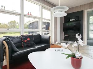 a living room with a black leather couch and a table at Holiday home Hjørring IV in Lønstrup