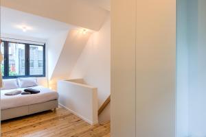 biała sypialnia z łóżkiem i oknem w obiekcie Stylishly furnished private home in a vibrant area w Antwerpii