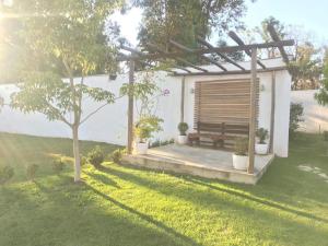 een houten bank onder een pergola in een tuin bij Chácara Recanto do Sossego em Mairinque-SP in Aluminio