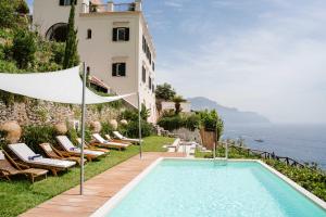 - une piscine sur le côté d'un bâtiment avec des chaises dans l'établissement AMALFI - VILLA DI LUSSO A PICCO SUL MARE, à Amalfi