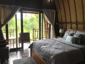 1 dormitorio con 1 cama y puerta de cristal grande en The Green ujung Villa en Ujung