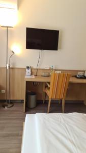 Zimmer mit einem Schreibtisch, einem TV und einem Stuhl in der Unterkunft Hotel Touristik in Neuenburg am Rhein