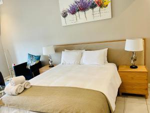 1 dormitorio con 1 cama grande con sábanas y almohadas blancas en Menlyn Maine Trilogy Hotel en Pretoria