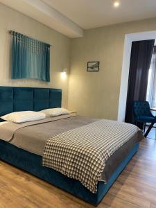 a bedroom with a bed with a blue headboard and a chair at Home Aparts in Zaporozhye