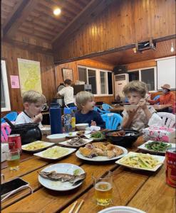 eine Gruppe von Kindern, die an einem Tisch sitzen und Essen essen in der Unterkunft Xijing Ecological Farm in Hualing