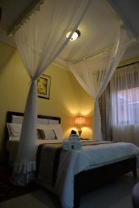 a bedroom with two beds with white drapes at Royal Victoria House in Kampala