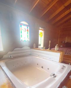 una grande vasca da bagno bianca in una stanza con finestra di Tal Nof Cabins a Manot