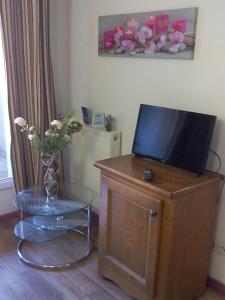 a television on top of a wooden cabinet with a vase of flowers at T2 Idéal Ski, rando et cures in Cauterets +1 photo