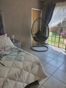 a bedroom with a bed and a chair in front of a window at Funky Dot Sleeping Spot in Kempton Park